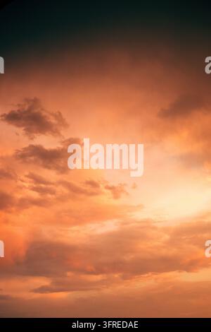 Turbulent storm front glowing with intense orange light beneath heavy dark clouds. Moody dramatic sky representing approaching severe weather, atmosph Stock Photo