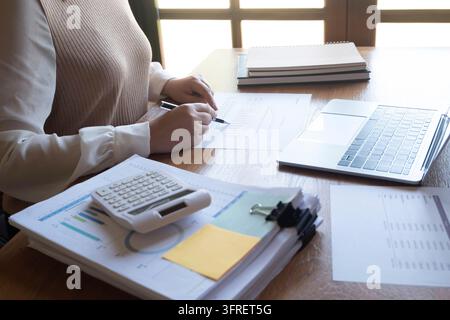 Cropped image of professional businesswoman, entrepreneur or accountant working on a financial report paperwork at her desk, using calculator or lapto Stock Photo