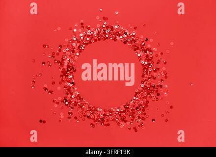 Sequins red confetti lined in a round frame red background. Abstract festive composition place for text. Valentine's Day holiday concept Stock Photo