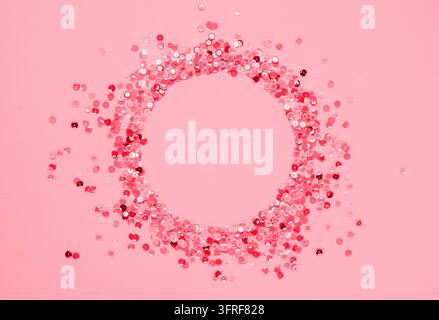 Sequins multicolored confetti lined in a round frame pink background. Abstract festive composition place for text Stock Photo