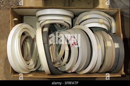 Pvc edge banding rolls in various colors and widths filling a cardboard box, providing essential supplies for woodworking, cabinet making, and furnitu Stock Photo