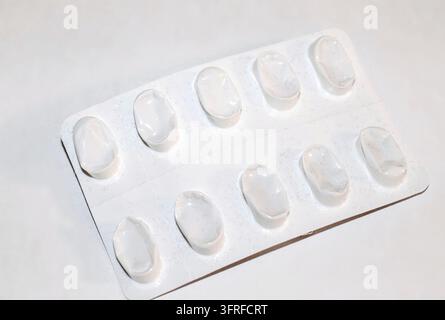 Packs of white pills packed in blisters with copy space isolated on a white background Focus on foreground, soft bokeh. Pharmacy drugstore concept Stock Photo
