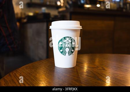 Starbucks coffee cup on wooden table in cafe. London, UK, 8 July 2023 Stock Photo