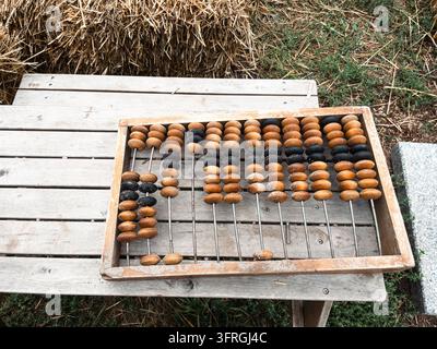 Vintage wooden abacus placed on rustic bench near straw bale outdoors Stock Photo