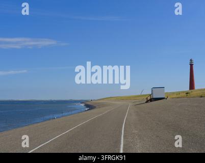Cycle route along sea dike with Lange Jaap lighthouse, North Holland Stock Photo