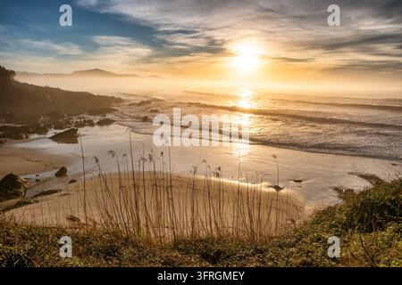 Golden sunset over ocean waves and sandy beach in Cantabria, Northern Spain Stock Photo