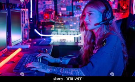Gamer woman streaming game online in a dark room, Woman hacker sitting in front computer typing on keyboard hacking servers in neon light, Female hack Stock Photo