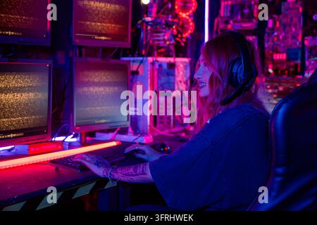 Gamer woman streaming game online in a dark room, Woman hacker sitting in front computer typing on keyboard hacking servers in neon light, Female hack Stock Photo