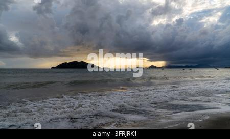 Fethiye, Turkey, storm clouds over the Mediterranean Sea at sunset, with waves rolling onto the beach and dark islands on the horizon Stock Photo