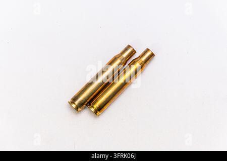 Two brass cartridge cases lie diagonally isolated on a clean white background. Stock Photo