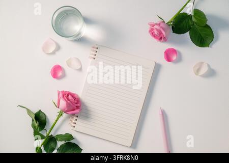 A beautiful arrangement featuring pink roses, a notebook, and elegant Stock Photo