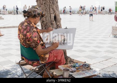 Street artist painting a watercolor in a sunny square Stock Photo