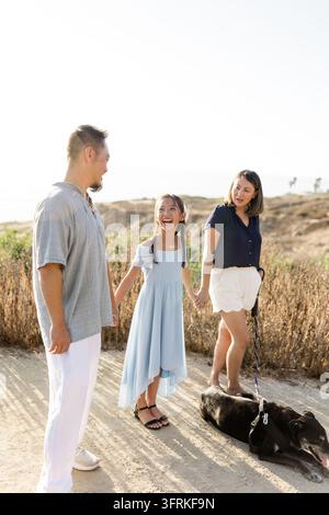 Happy Asian family holding hands on a sunny walk Stock Photo