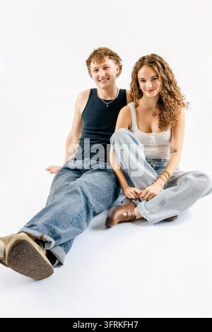 Stylish young couple sitting together on a white background Stock Photo