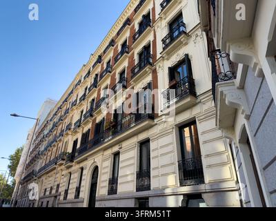 MADRID, SPAIN - OCTOBER 08, 2026 Historic Madrid building facade features tall windows, decorative cream stonework, and black iron balconies. Resident Stock Photo