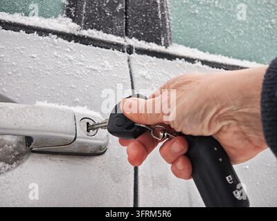 A hand tries to unlock a car door covered with snow and ice during a ...