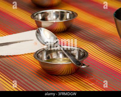 Two small empty stainless steel bowls and one with spoon on a striped colorful tablecloth. Stock Photo
