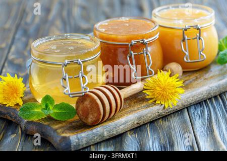 Honey in glass jars and dipper for honey on a wooden stand, selective focus Stock Photo