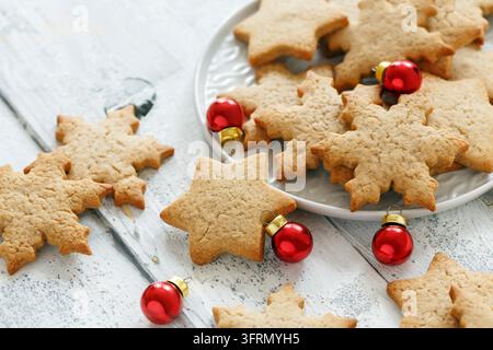 White plate with ginger cookies and red Christmas balls on wooden table, selective focus Stock Photo