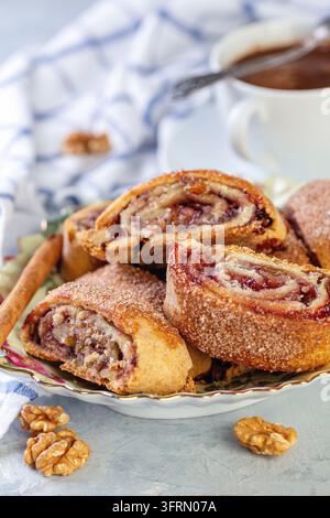 Rugelach with jam, nuts and raisins and a cup of black coffee on a grey textured background, selective focus Stock Photo