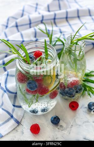 Lemonade with berries and tarragon in jars on the table with a linen towel, selective focus Stock Photo