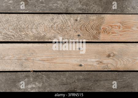 Top view flat lay photograph of rustic, weathered wooden boards and planks showing natural wood grain patterns, textures, and construction screws. Per Stock Photo