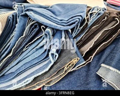 Close-up of a stack of folded denim jeans, showcasing a variety of colours and textures, perfect for fashion and retail concepts Stock Photo