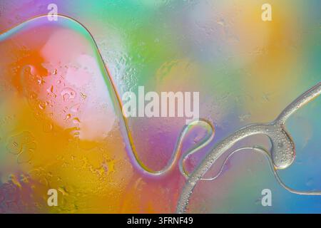 Colorful abstract liquid texture with translucent flowing shapes, water droplets, and iridescent reflections on a glass-like surface in vibrant pastel Stock Photo
