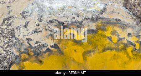 Aerial view of an abstract Andean landscape featuring vivid yellow mineral deposits, gray sediment, and organic natural patterns across a textured ear Stock Photo
