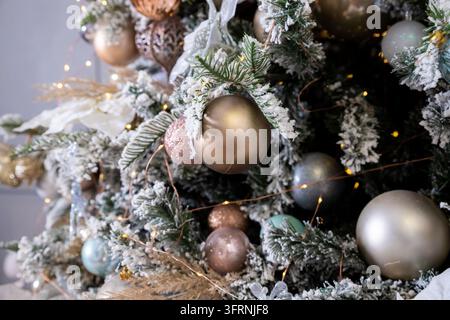 artificial lush cast snowy Christmas tree spruce decorated with silver, bronze, golden balls. garland close up.Festive winter holidays composition. Stock Photo