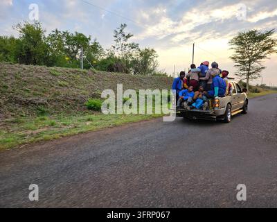 JOHANNESBURG - NOV 21, 2023: Truck pickup is driving down a road with a group of people sitting in the back. The truck is white and has a mirror on the back during safari in South Africa Stock Photo