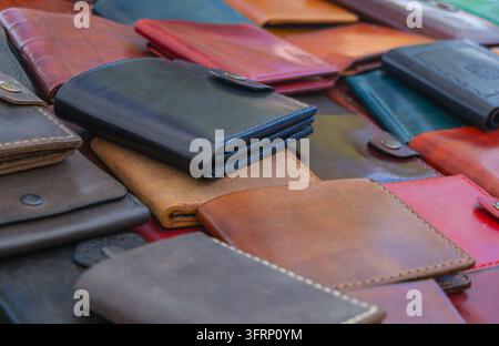 Close-up of handmade leather wallets and cases in black, brown, red and blue tones, showing stitched edges, snap closures and artisan craftsmanship at Stock Photo