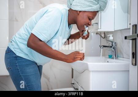 Woman brushing teeth in bathroom maintaining dental hygiene Stock Photo
