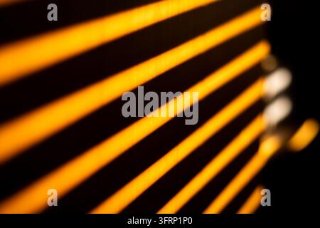 Abstract orange light stripe pattern with glowing diagonal line on black background in close up detail view. Modern geometric texture with warm glowin Stock Photo