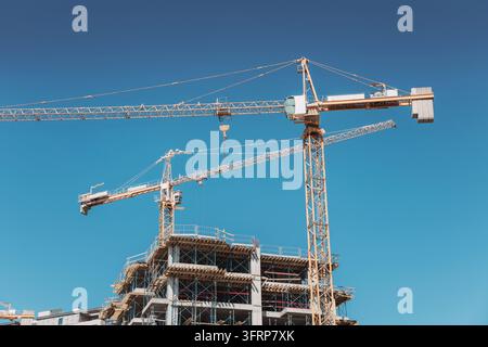 Tower cranes constructing a new residential building, symbolizing growth, development, and progress in an urban landscape Stock Photo
