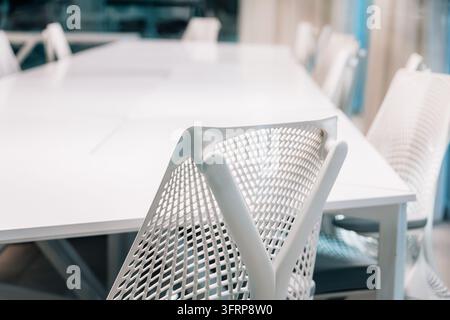 Bright and clean corporate meeting room, featuring a long white table and modern ergonomic chairs, ready for business Stock Photo
