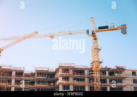 Tower cranes constructing a new residential building, symbolizing growth, development, and progress in an urban landscape Stock Photo