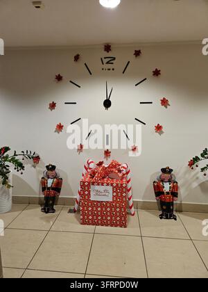 Large clock with the hands on the number 12 and 2. There are two men standing next to the clock christmas entrance elevator lift house. Text - Happy New Year and Merry Christmas! Stock Photo