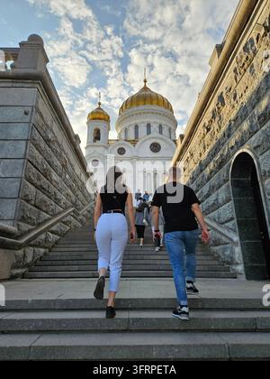 Man and a woman are walking up a set of stairs to church. The woman is wearing a black shirt and white pants Stock Photo