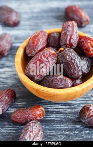 Dried fruits of date palm in bowl on an old wooden table, selective focus Stock Photo