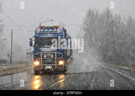 Blue Scania truck transporting goods on road in winter sleet and snow, creating difficult conditions for traffic. Salo, Finland. November 29, 2019 Stock Photo