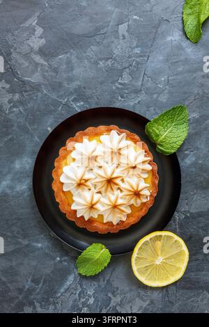 Plate of lemon tart and meringue on dark stone background, selective focus Stock Photo