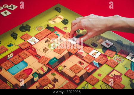 July 27,2024 Bereza, Belarus. Human hand placing a tile on a colorful game board, strategic tabletop board game process, leisure activity close up Stock Photo