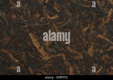 Close-up of dark, fermented Yunnan shu pu-erh tea leaves with brown and deep earthy tones. The dried leaves form a dense textured surface. Stock Photo