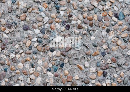 Pebble aggregate concrete surface with mixed stones embedded in cement - texture background. Stock Photo