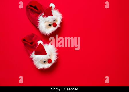 New year, Christmas slippers in form of santa claus with white soft fur on red background with place for text. Funny, cozy, fluffy children shoes Stock Photo