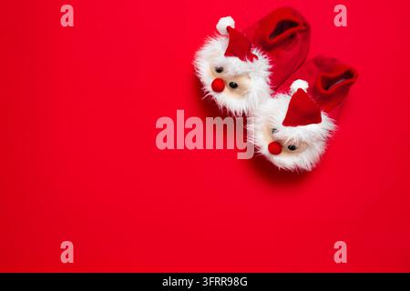 New year, Christmas slippers in form of santa claus with white soft fur on red background with place for text. Funny, cozy, fluffy children shoes Stock Photo