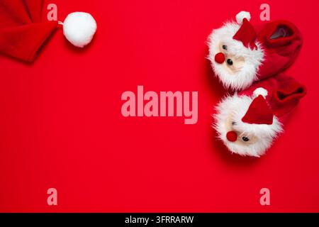 New year, Christmas slippers in form of santa claus with white soft fur on red background with place for text. Funny, cozy, fluffy children shoes Stock Photo