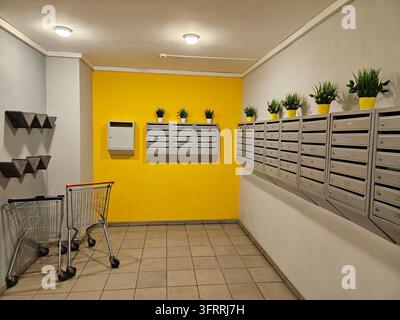 The room is yellow and has a cart and potted plants, mailboxes in the entrance of the house Stock Photo