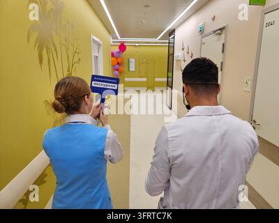 MOSCOW - SEP 7, 2025: Woman and a man are standing in a hallway, looking at a sign that says Moscow medicine excursion. The woman is holding a plate, and the man is wearing a white lab coat. Stock Photo